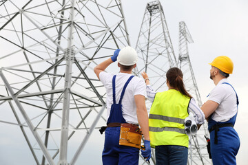 Professional engineers working on installation of electrical substation outdoors