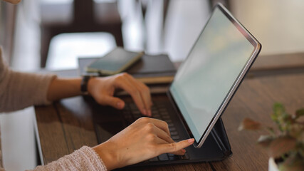 Female hands typing on tablet keyboard on wooden table, include clipping path