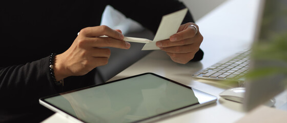 Male hand working with colour chart and tablet on white worktable