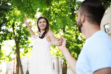 Obraz premium Lovely young couple dancing together in park on sunny day