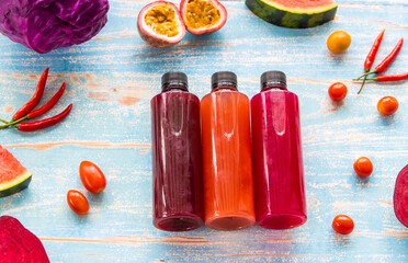 several bottles of homemade juice from various ingredients of fruits, spice, and vegetables on rustic wooden table from high angle view. Health lifestyle detox and diet food and drinks concept