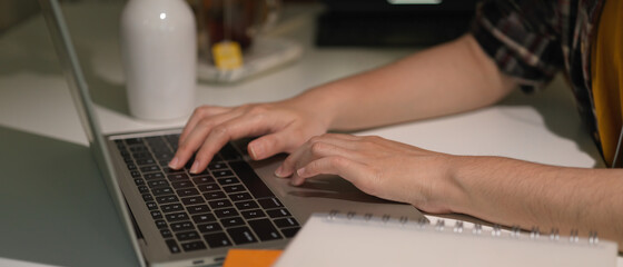 Female hands typing on laptop keyboard on white table in home office room