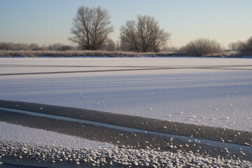 Breath of winter, first ice on the lake, dawn on a frosty morning with frost on the grass, close-up...