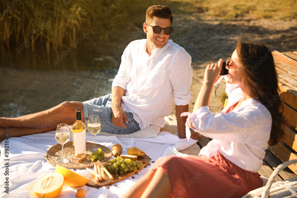 Poster Woman taking picture of boyfriend on pier at picnic