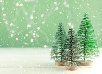 Miniature toy Christmas trees on a wooden table with snow. Imitation realistic scene. Banner