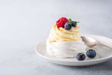 Delicious Pavlova cake with whipped cream and fresh berries on white plate. Stone background. Selective focus
