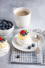 New Zealand Pavlova cake with whipped cream and fresh berries and mug with coffee