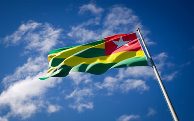 Beautiful national state flag of Togo fluttering at sky background. Low angle close-up Togo flag 3D artwork.