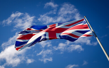 Beautiful national state flag of UK fluttering at sky background. Low angle close-up UK flag 3D artwork.