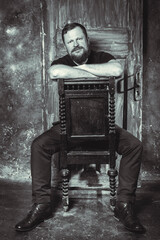 Mature bearded man sitting on vintage door background