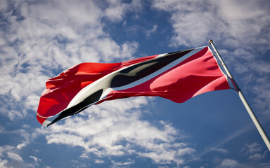 Beautiful national state flag of Trinidad and Tobago fluttering at sky background. Low angle close-up Trinidad and Tobago flag 3D artwork.
