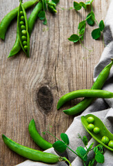 Pods of green peas with pea leaves  on a old wooden background. Organic food.
