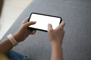 Mockup image of woman is using a black mobile phone with blank screen horizontally for watching at home.