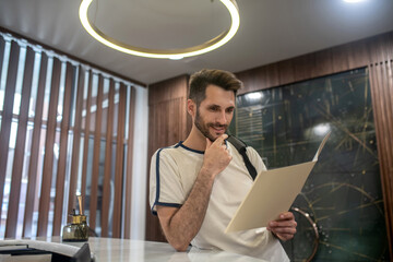 Male customer standing at recepion desk, studying carefully price list
