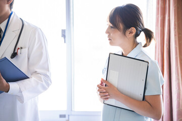 入院患者の回診に来た女性看護師と医師