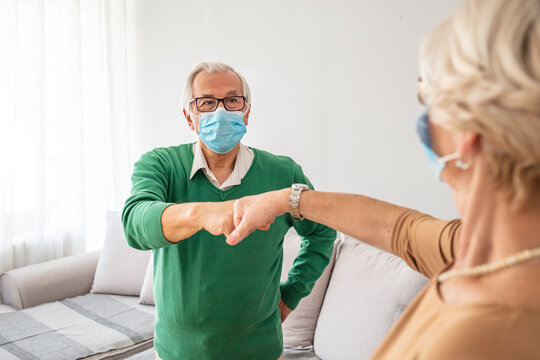 Male And Female Seniors Fist Bumping, Group Of Senior People With Protective Face Masks. New Normal Greeting With Fist Bump. Two People Wearing Protective Face Mask And Greeting With Fist Bump