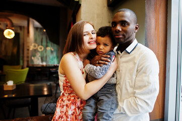 Happy multiethnic family with boy kid spend time at restaurant. Relationships of african man and white european woman.