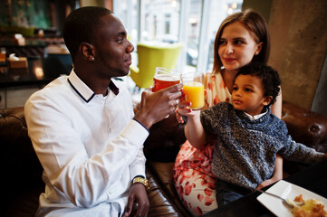 Happy multiethnic family with boy kid spend time at restaurant. Relationships of african man and white european woman.