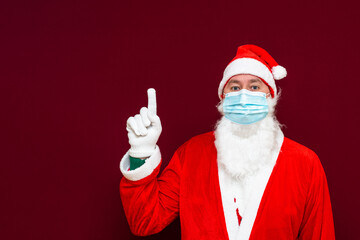 Fototapeta na wymiar Side view Santa Claus man wears face mask shows to copy space coronavirus virus covid-19 during quarantine.