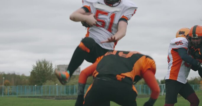 American football, football team in the game, training aggressive opposition during the game, the man breaks through with the ball in his hands and falls to the ground, 4k slow motion.