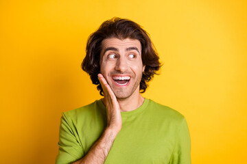 Photo of funky crazy guy palm cheekbone look side empty space wear green t-shirt isolated yellow color background
