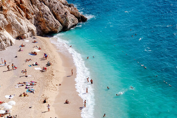 View of the turquoise beach. Beautiful Kaputas Beach (Turkey) with people resting under the sun and in the sea