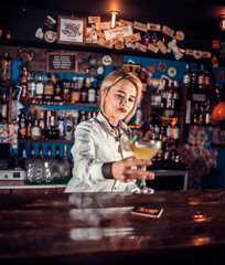 Expert woman bartender pouring fresh alcoholic drink into the glasses at the night club