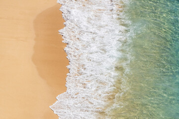 Beautiful empty beach from above with turquoise sea water and clean sand. Sea foam and waves.