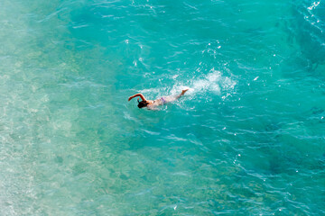Swimming man in the sea. Swimmer in the clear turquoise sea and clear water under the sun. Freediving and swimming concept