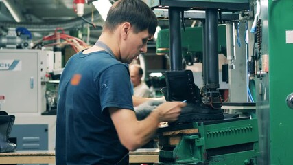 Male worker is putting an unfinished boot under a press