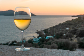 A glass of white wine. Wine against the backdrop of the sea coast and a sunny summer beach. Wine tasting and relaxation at the resort