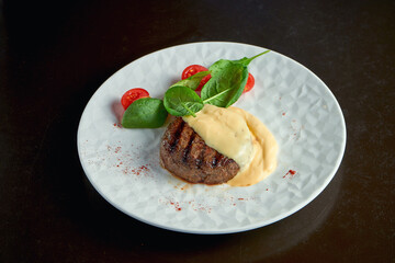 Classic beef steak with cheese sauce in a white plate with spinach