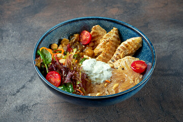 Buddha bowl with turkey, tomatoes, vegetables and clear rice noodles in a blue plate. Selective focus