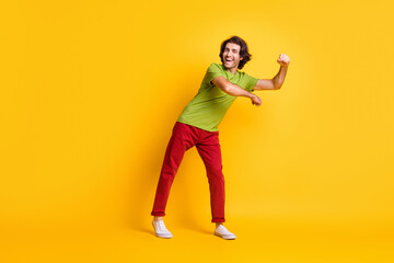 Fototapeta na wymiar Full length body size photo of careless playful man wearing red trousers dancing laughing isolated on vivid yellow color background