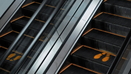 staircase escolator in a shopping center with a footprint sign for keeping a social distance