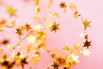 Fototapeta na wymiar Blurred Golden star sprinkles on pink. Festive holiday background. Celebration concept. Top view, flat lay. Horizontal