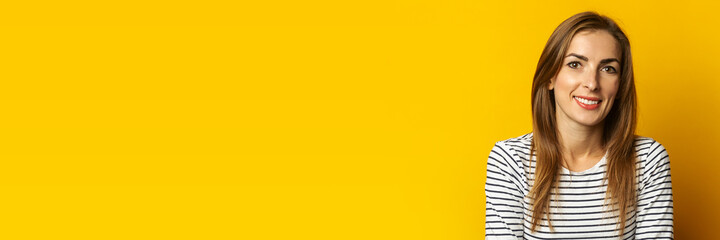 Young woman with a smile on a yellow background. Banner