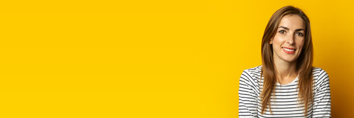Naklejka premium Young woman with a smile on a yellow background. Banner