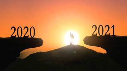 2021 concept: Silhouette of year 2021 and disabled person  on mountain  with city sunset  background