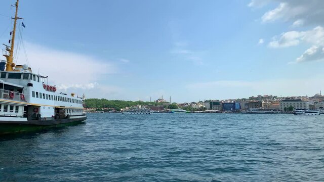 Footage of cruise tour boats passing on Golden Horn part of Bosphorus in Istanbul. Galata bridge and old neighborhood called "eminonu" are in the view. It is a sunny summer day. Camera pans right.