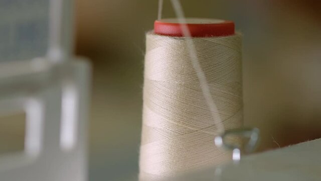 CLOSE UP unwinding thread spool of a running sewing machine