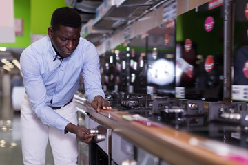 Young man selecting new cooking top in store of household appliances