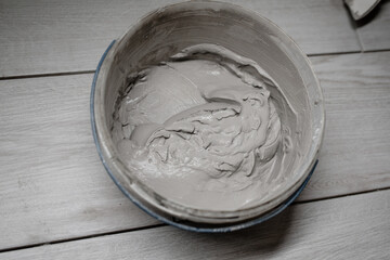 putty cement in bucket on floor for rebuild wall at home - can use to display or montage on product. texture of cement mortar for plastering walls - repair, construction, interior decoration.