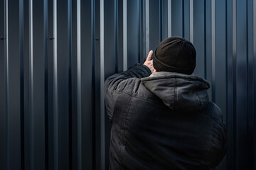 Metal fence installation. The worker is screwing the screw into the metal fence.