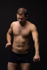 Handsome man in underwear on the black background. Muscular and athletic. 
Underwear man portrait. Male underwear model in studio

