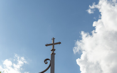 Metal cross located on the perimeter of a religious cemetery, on a sunny day