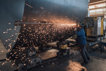 Worker cutting steel tanks with flying sparks