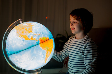 Little child, looking at illuminated globe, exploring