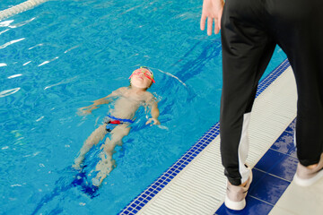 Toddler swimming training in the pool. Swimming training for a child. Development of children's...