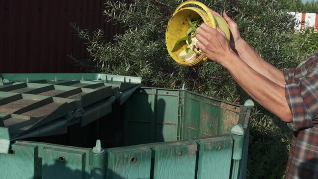Slow motion person throws kitchen food waste into compost heap to make organic fertilizer. Composting - eco-friendly recycling technology. Kitchen waste leftovers to fertilizer. Sustainable living. 